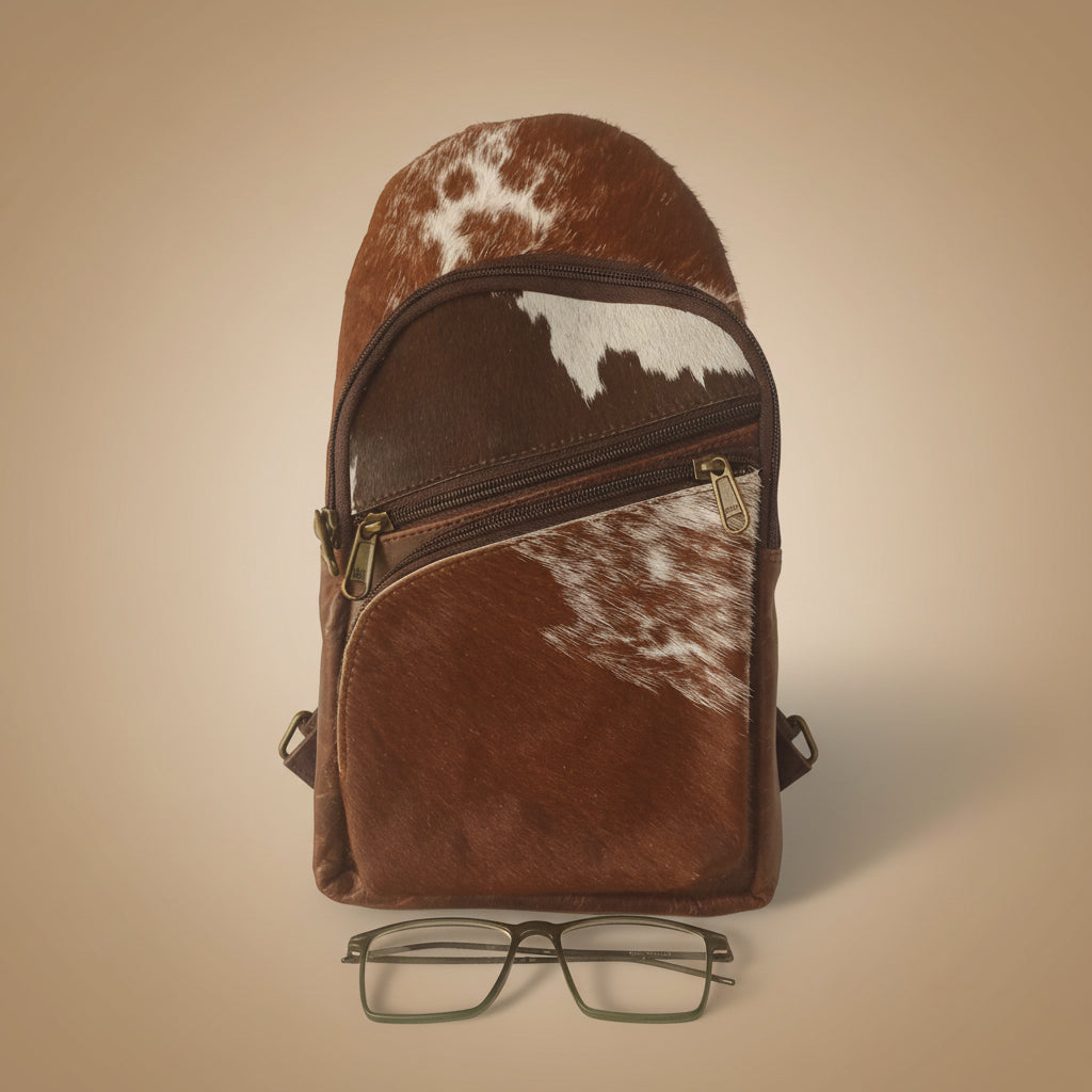 Brown leather bag with cowhide pattern and glasses on a white background