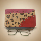 Leopard print case with pink accents and a pair of glasses on a white background