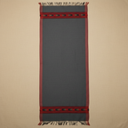 Gray woven blanket with red border and fringes on a beige background