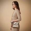 Brown and white cowhide leather bag on a beige background