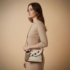 Brown and white cowhide leather bag on a beige background
