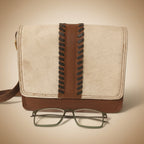 Notebook with brown leather strap and glasses on a white background
