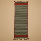 Striped woven rug with red and green pattern on a beige background