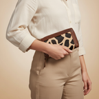 Person holding a clutch with leopard print design against a beige background